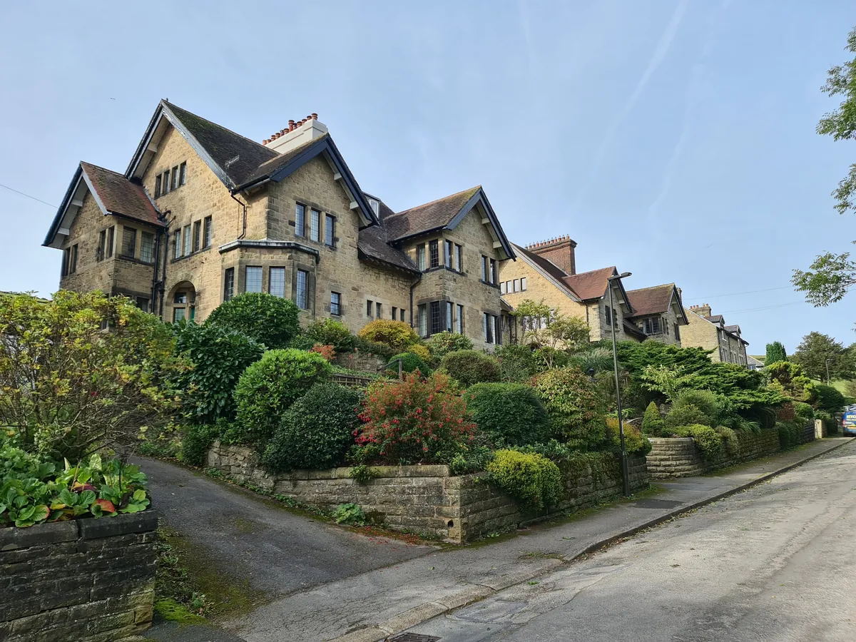 Large gabled stone houses above sloping gardens on Lightwood Road in Buxton
