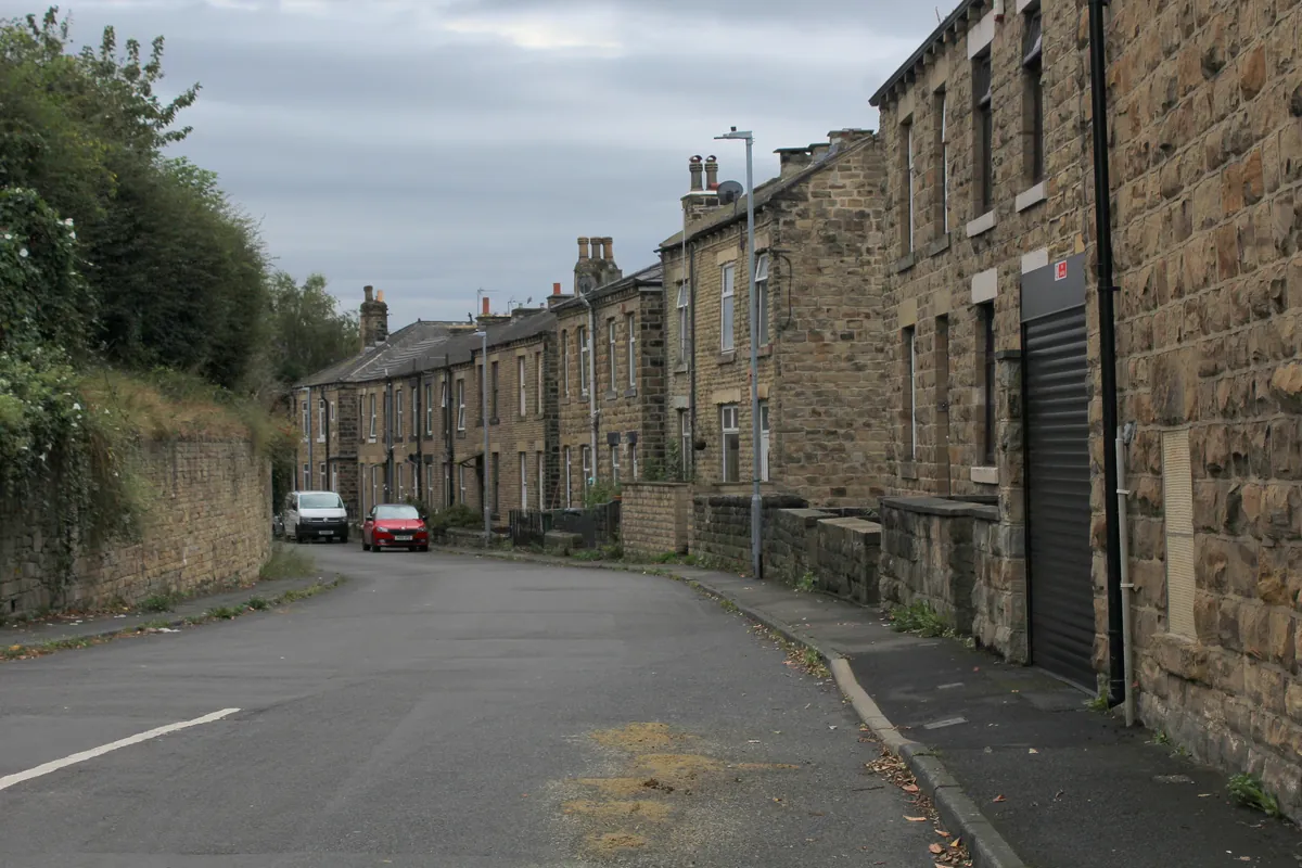 Stone terraced houses along a sloping street on Oaks Road in Batley