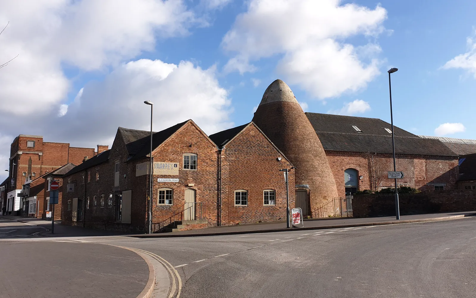 The red-brick buildings and bottle kiln of Sharpe's Pottery Museum on a street corner in Swadlincote